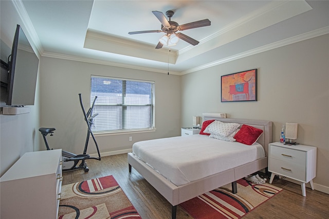 bedroom featuring hardwood / wood-style floors, a raised ceiling, ceiling fan, and ornamental molding