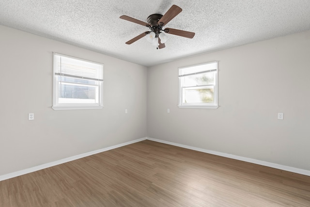 unfurnished room featuring plenty of natural light, a textured ceiling, and hardwood / wood-style flooring