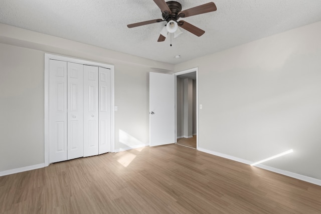 unfurnished bedroom with ceiling fan, a closet, a textured ceiling, and hardwood / wood-style flooring