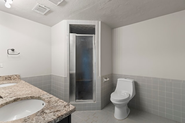 bathroom with tile patterned flooring, vanity, toilet, and tile walls