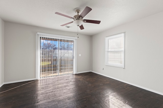 unfurnished room with a textured ceiling, a wealth of natural light, ceiling fan, and dark hardwood / wood-style floors