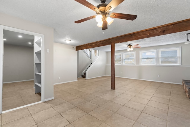 basement featuring ceiling fan, light tile patterned floors, and a textured ceiling