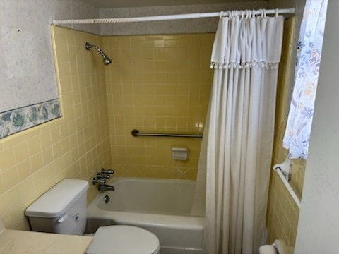 full bathroom with vanity, toilet, shower / bath combo with shower curtain, and tile walls