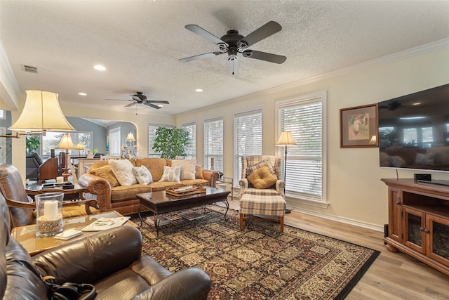 living room featuring wood-type flooring, a textured ceiling, ceiling fan, and crown molding