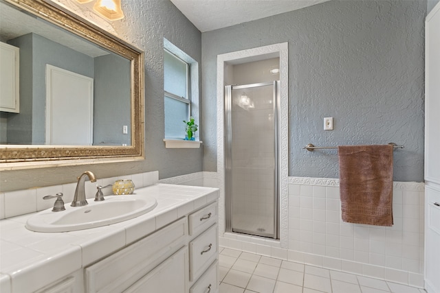 bathroom featuring tile patterned flooring, a textured ceiling, vanity, and a shower with shower door