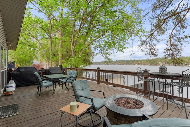 wooden deck with a fire pit, a water view, and grilling area