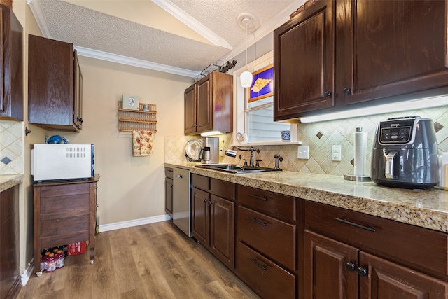 kitchen with crown molding, lofted ceiling, decorative light fixtures, a textured ceiling, and light wood-type flooring