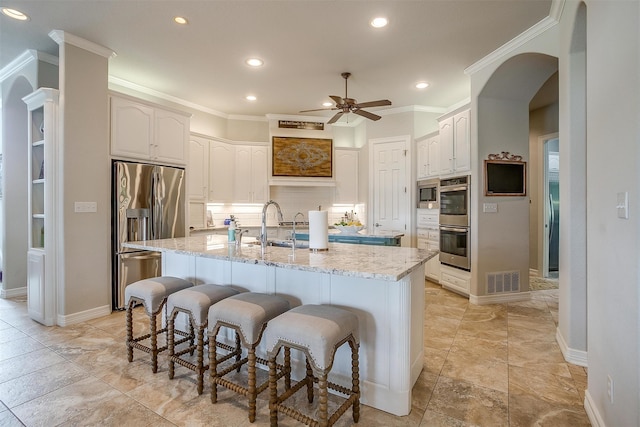 kitchen featuring tasteful backsplash, white cabinetry, a center island with sink, and appliances with stainless steel finishes