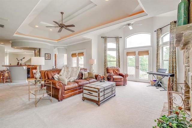 living room featuring a raised ceiling, light carpet, french doors, and ceiling fan