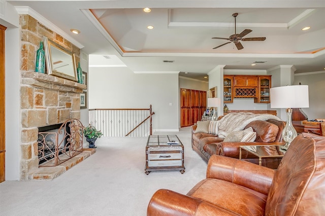 living room featuring ceiling fan, a raised ceiling, a fireplace, carpet, and ornamental molding