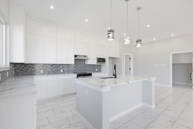 kitchen with appliances with stainless steel finishes, an island with sink, pendant lighting, sink, and white cabinetry