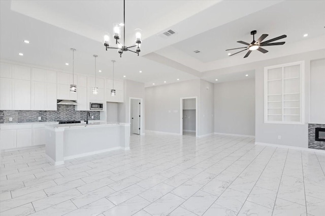 kitchen featuring stainless steel microwave, sink, and ceiling fan with notable chandelier