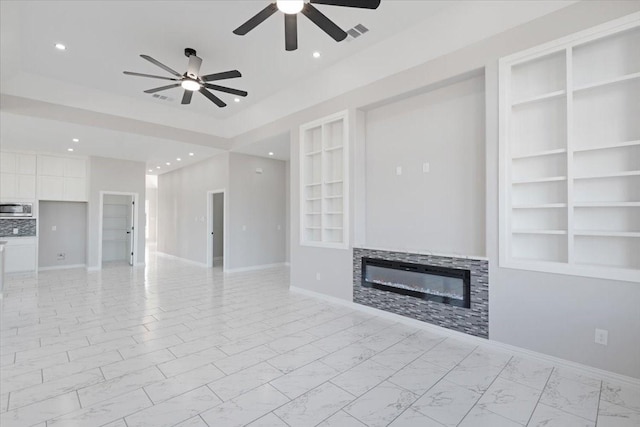 unfurnished living room featuring built in shelves and ceiling fan