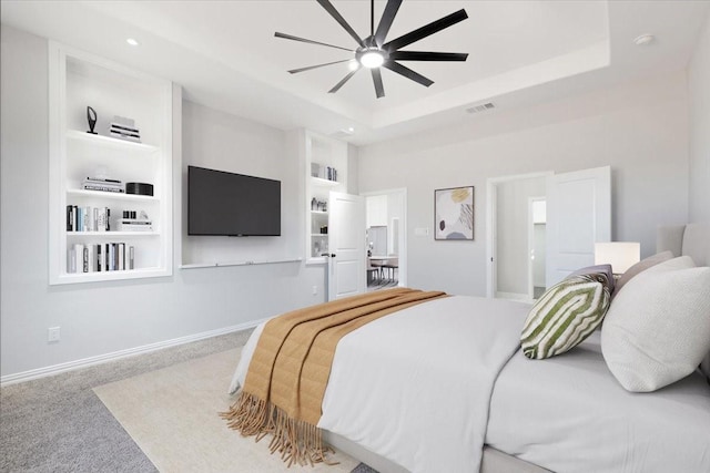 bedroom with a raised ceiling, ceiling fan, and light colored carpet