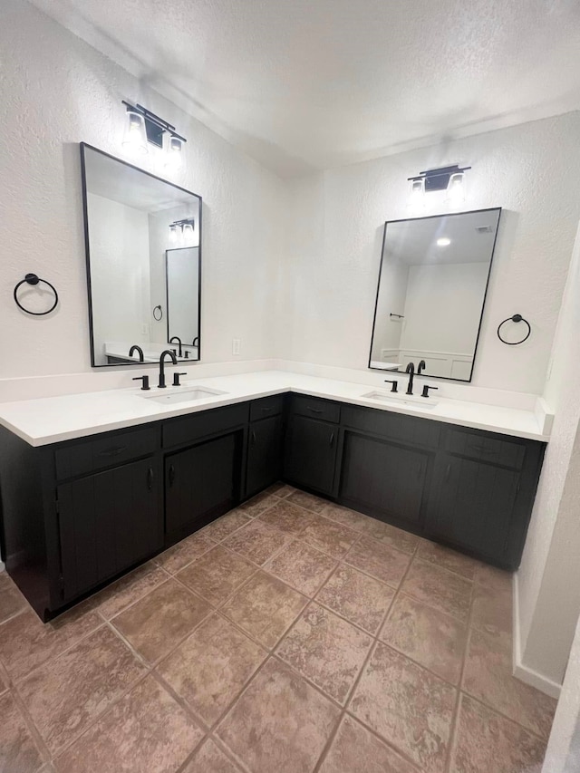 bathroom with a textured ceiling, vanity, and a textured wall