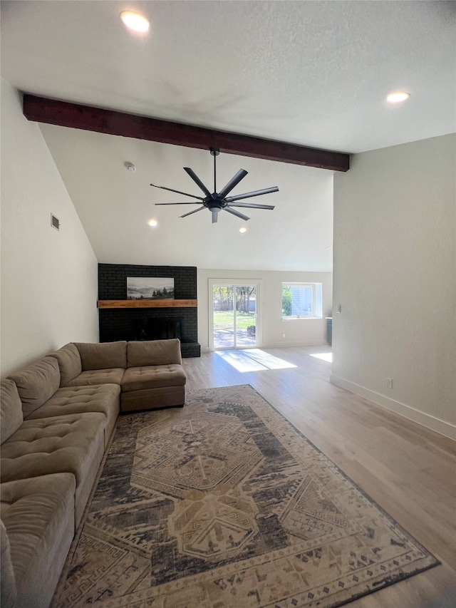 living room with hardwood / wood-style flooring, vaulted ceiling with beams, ceiling fan, and a brick fireplace