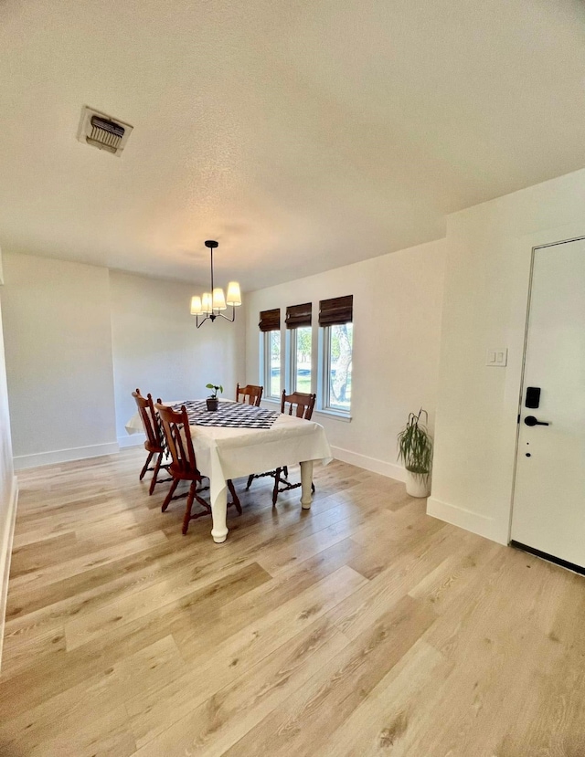 dining room featuring visible vents, a textured ceiling, light wood-style floors, an inviting chandelier, and baseboards