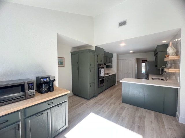 kitchen with visible vents, stainless steel appliances, a sink, light countertops, and light wood-style floors