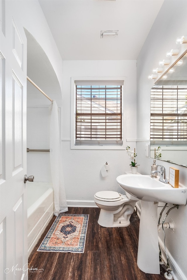 bathroom featuring hardwood / wood-style flooring, toilet, and shower / bathtub combination with curtain