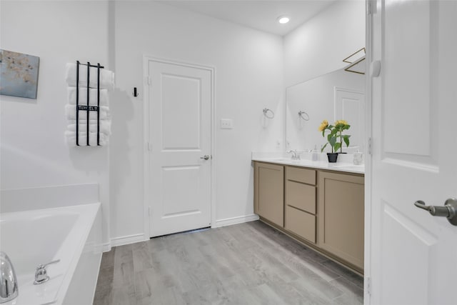 bathroom featuring a washtub, vanity, and hardwood / wood-style flooring