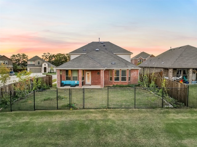 back house at dusk featuring a lawn, a patio area, and an outdoor hangout area