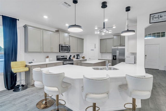 kitchen with pendant lighting, a breakfast bar, light hardwood / wood-style floors, and stainless steel appliances