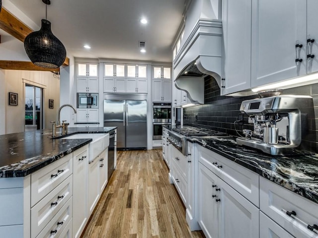 kitchen featuring built in appliances, white cabinets, and decorative light fixtures