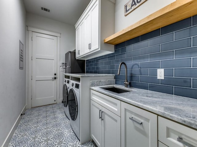 clothes washing area featuring sink, cabinets, and washing machine and clothes dryer