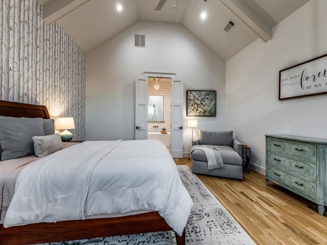 bedroom featuring ceiling fan, high vaulted ceiling, connected bathroom, light hardwood / wood-style floors, and beamed ceiling