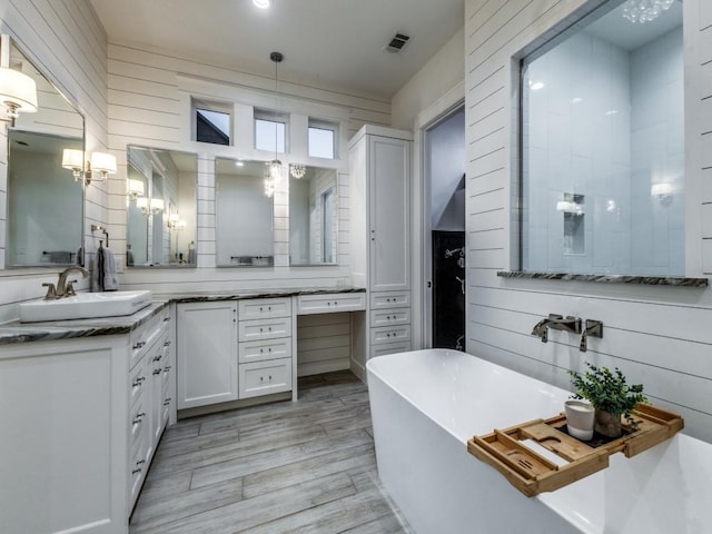 bathroom featuring a tub to relax in, wood walls, an inviting chandelier, vanity, and hardwood / wood-style floors