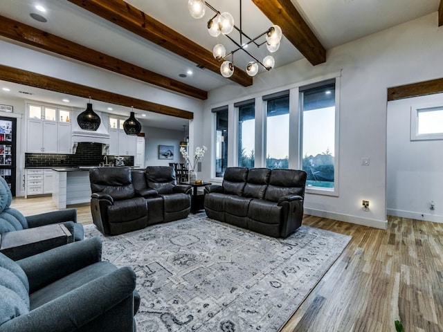 living room featuring beam ceiling, an inviting chandelier, and light wood-type flooring