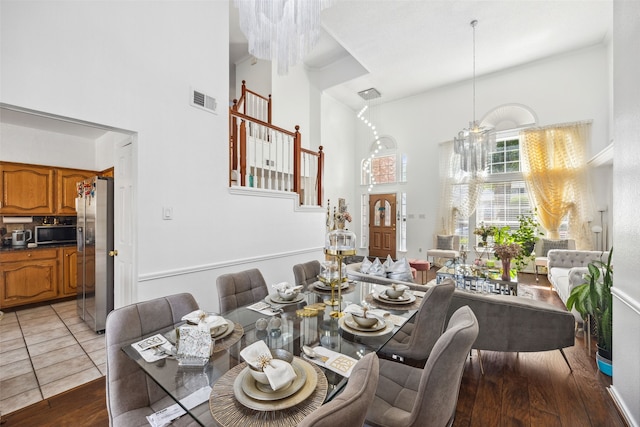 dining area with a high ceiling, dark hardwood / wood-style flooring, and an inviting chandelier