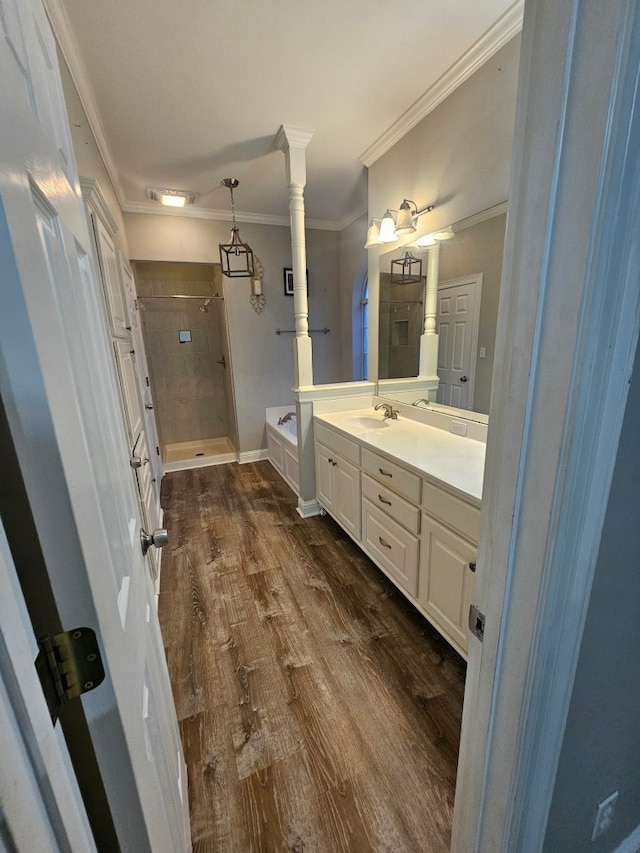 bathroom with ornate columns, crown molding, wood-type flooring, vanity, and independent shower and bath