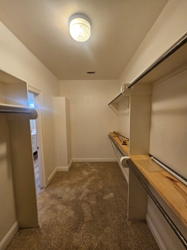 walk in closet featuring dark colored carpet