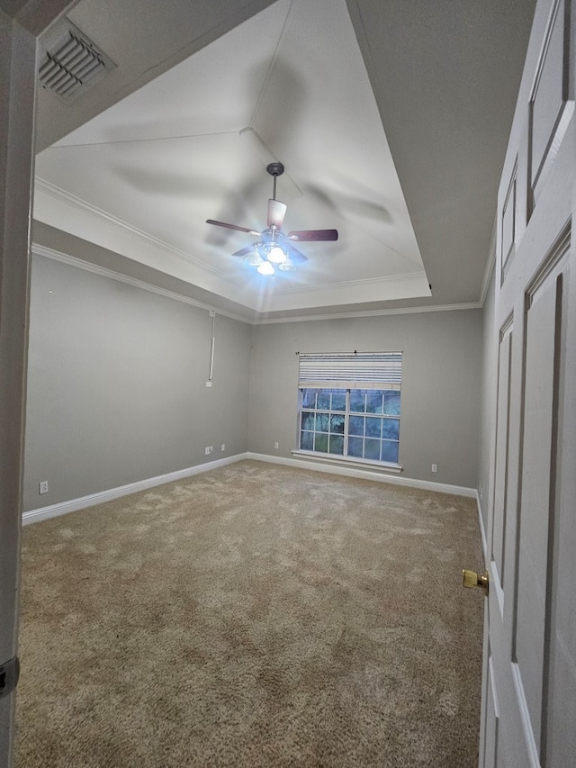 unfurnished bedroom featuring ceiling fan, carpet floors, crown molding, and a tray ceiling