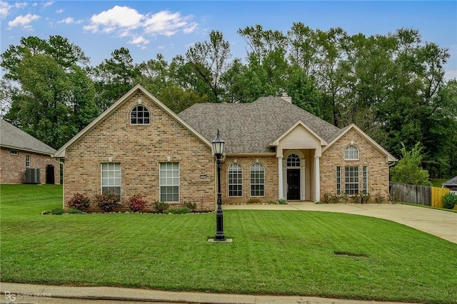 view of front of property featuring fence, a front yard, a shingled roof, brick siding, and a chimney