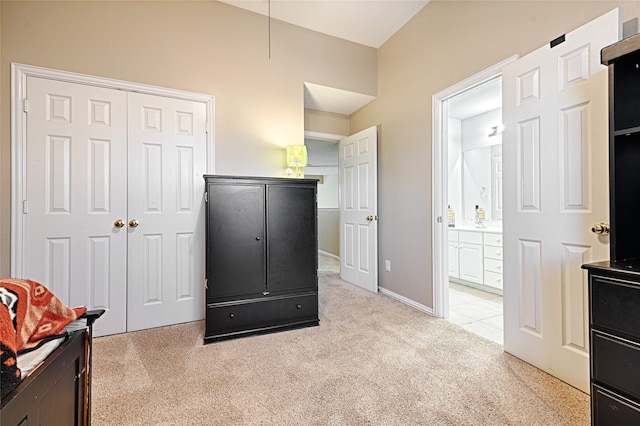 bedroom featuring light carpet, ensuite bath, and a closet