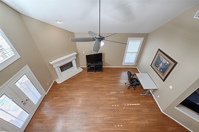 unfurnished living room with ceiling fan, a healthy amount of sunlight, and wood-type flooring