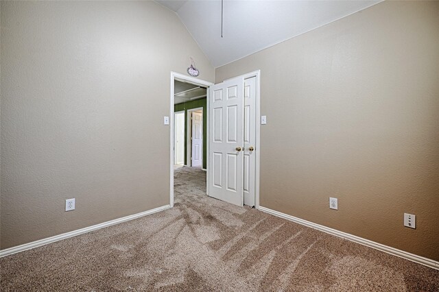 spare room featuring carpet and vaulted ceiling