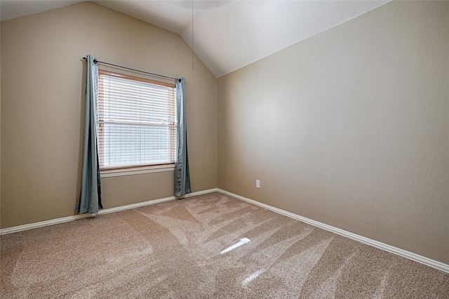 carpeted empty room with vaulted ceiling