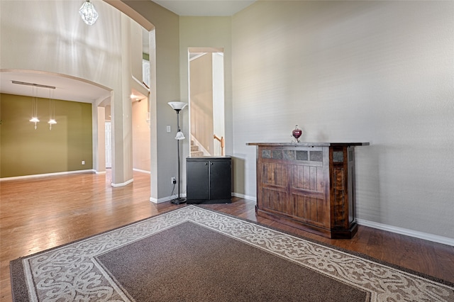 entryway featuring wood-type flooring, a high ceiling, and a chandelier