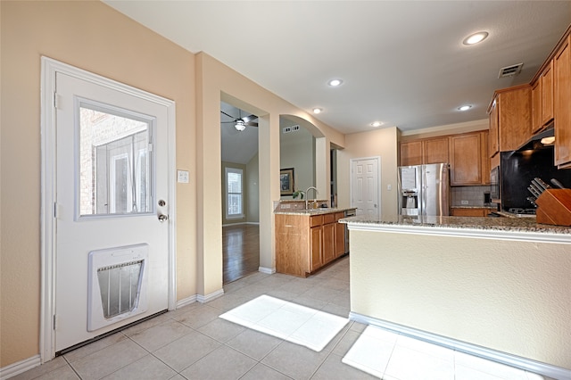 kitchen with decorative backsplash, light stone countertops, light tile patterned floors, stainless steel fridge with ice dispenser, and heating unit