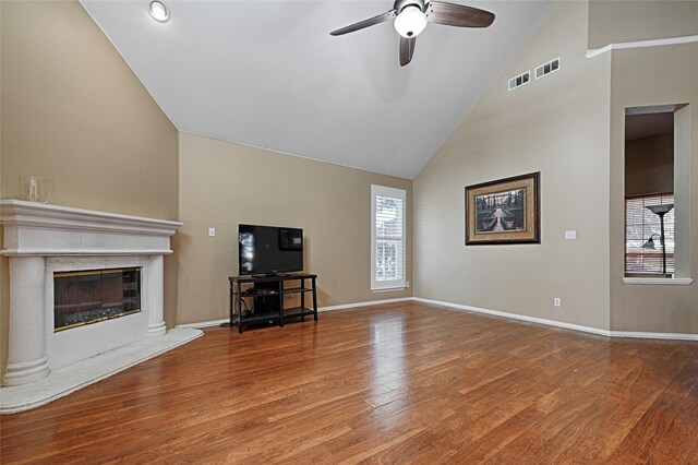 unfurnished living room with hardwood / wood-style floors, ceiling fan, a premium fireplace, and high vaulted ceiling