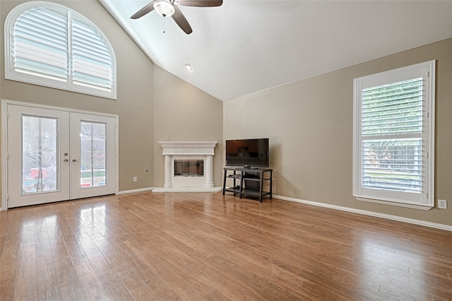 unfurnished living room featuring french doors, high vaulted ceiling, a healthy amount of sunlight, and light hardwood / wood-style flooring