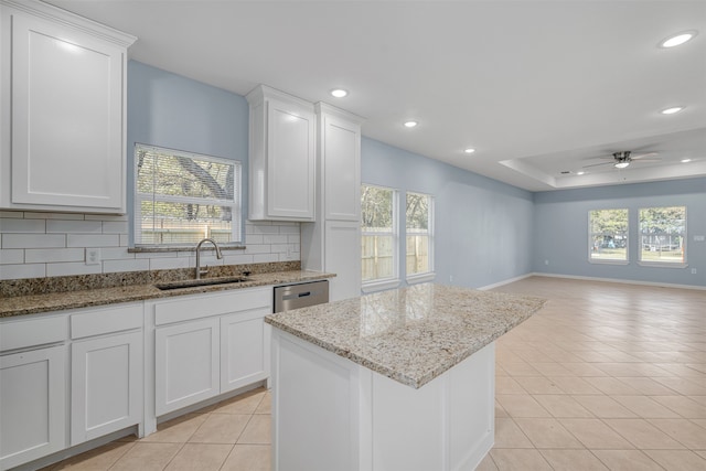 kitchen featuring backsplash, light stone counters, white cabinetry, and sink