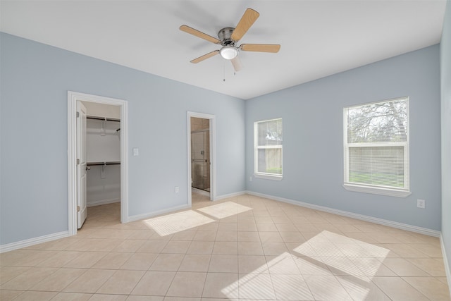 unfurnished bedroom featuring ensuite bath, a spacious closet, ceiling fan, a closet, and light tile patterned floors