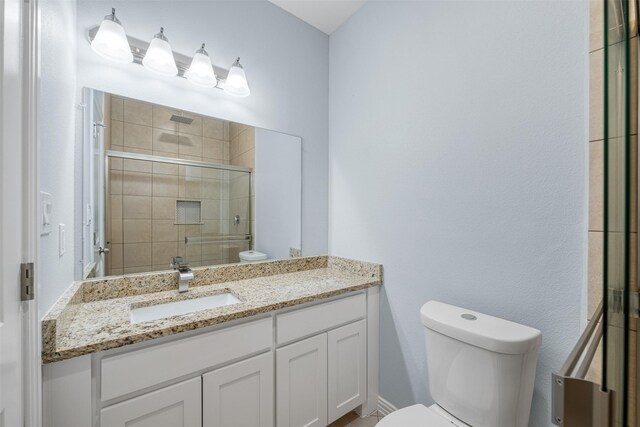 bathroom with an enclosed shower, vanity, and toilet