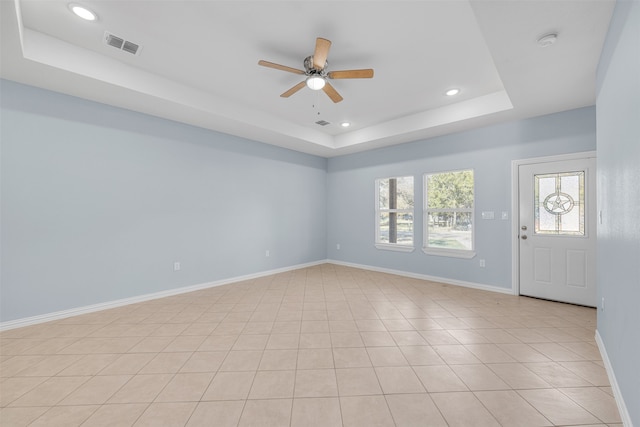 tiled spare room with a tray ceiling and ceiling fan