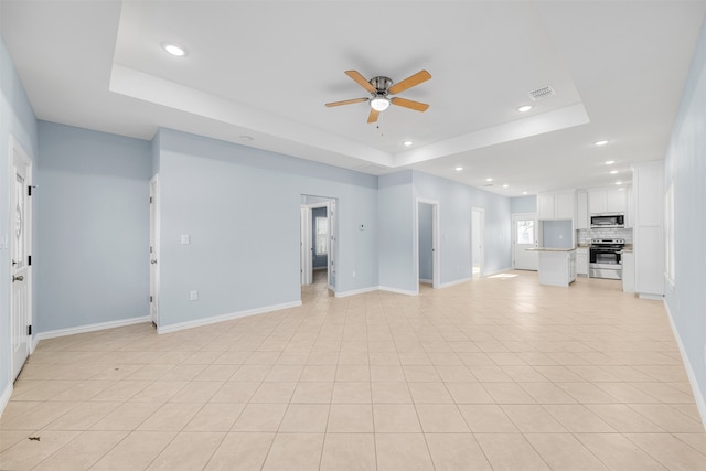 unfurnished living room featuring light tile patterned floors, a tray ceiling, and ceiling fan