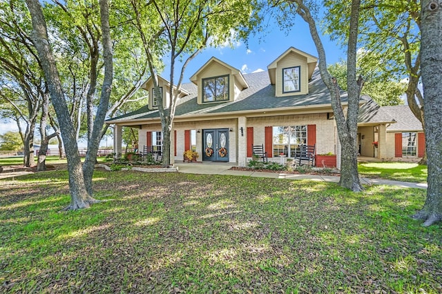 new england style home with covered porch, a front yard, and french doors